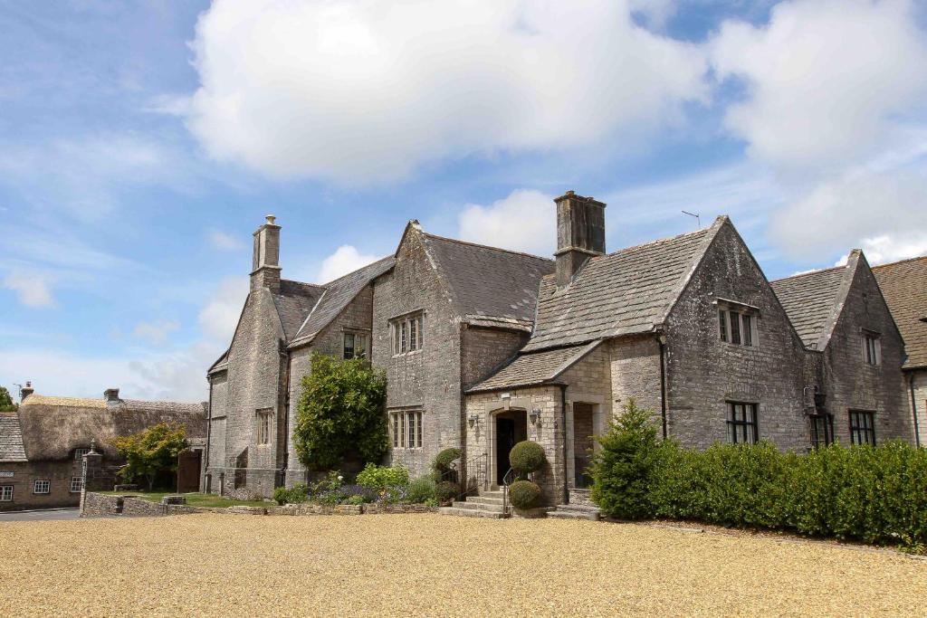 une grande maison en pierre avec un toit dans l'établissement Mortons Manor, à Corfe Castle