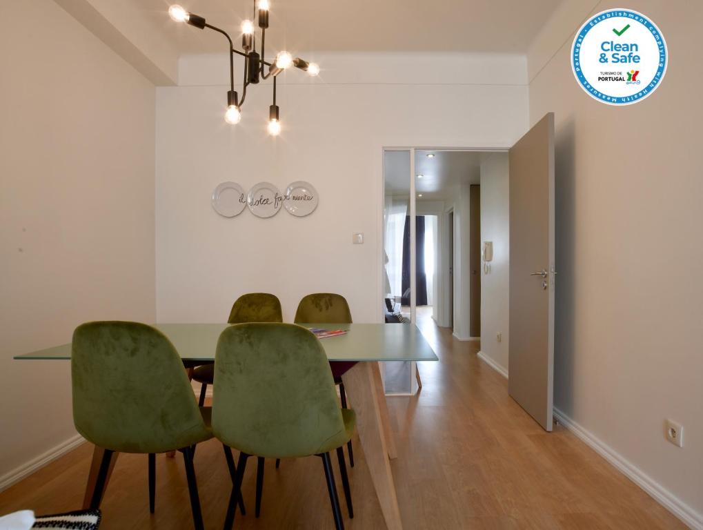 uma sala de jantar com uma mesa e cadeiras verdes em Spot Apartments no Porto