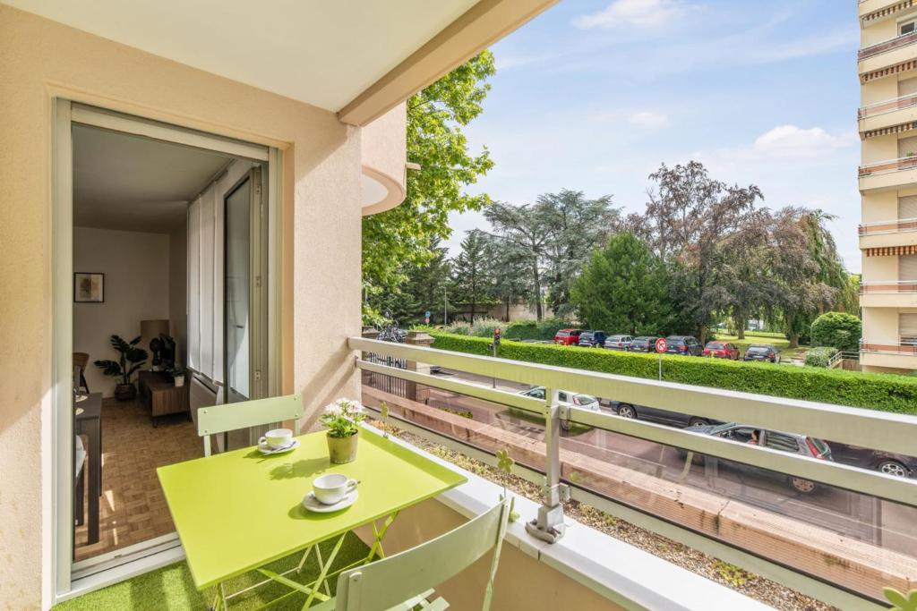 d'un balcon avec une table et des chaises vertes ainsi qu'une fenêtre. dans l'établissement Beautiful 1-bedroom w balcony and garden near Lyons city center Welkeys, à Caluire-et-Cuire