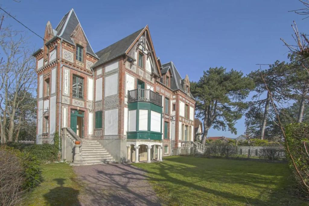une ancienne maison en briques avec une tour sur une pelouse dans l'établissement Duplex Margareth Welkeys, à Cabourg