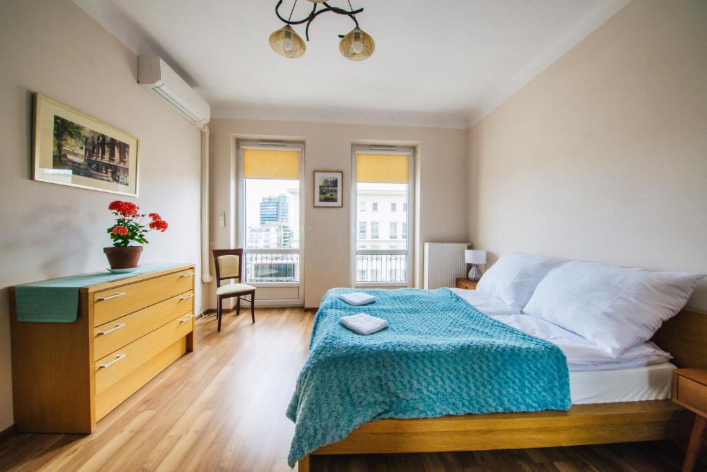 a bedroom with a bed with a blue blanket on it at Apartment Metro Politechnika in Warsaw