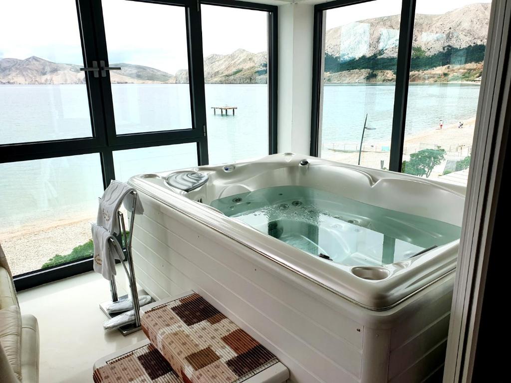 bañera grande en una habitación con ventanas en Apartments Toni en Baška