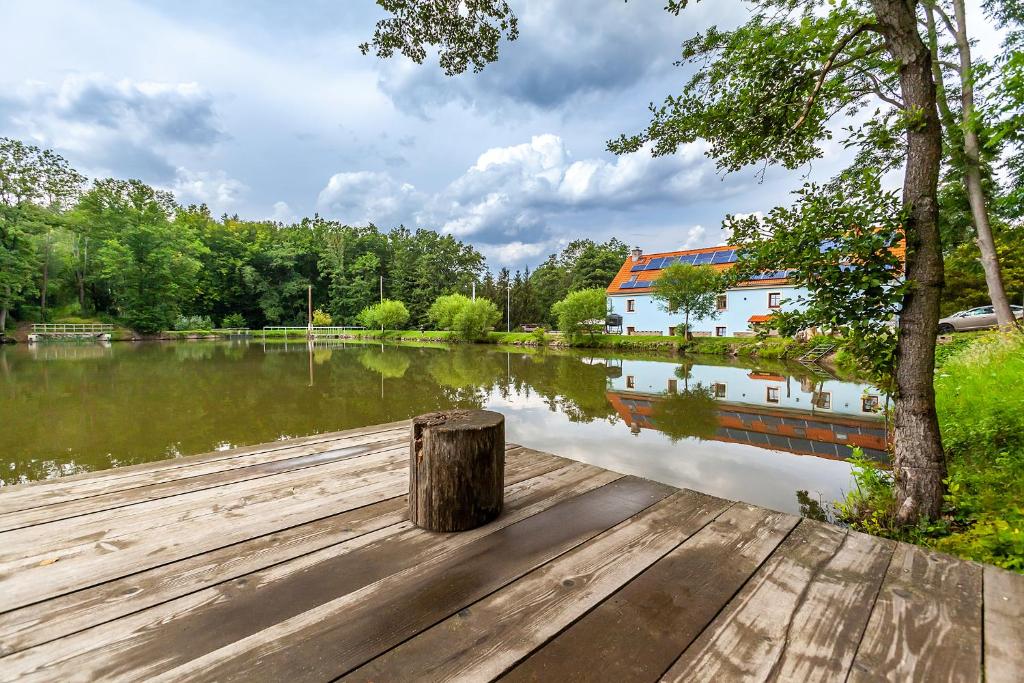 ein Holzsteg neben einem See mit einem Gebäude in der Unterkunft Penzion Bačalský mlýn in Morašice