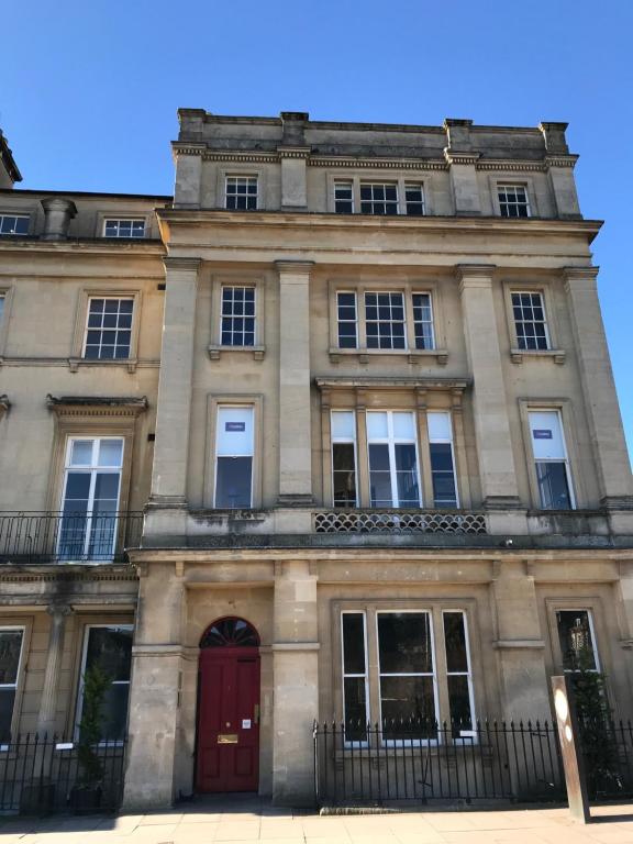 a large stone building with a red door at The Loft, Flat 3 in Bath