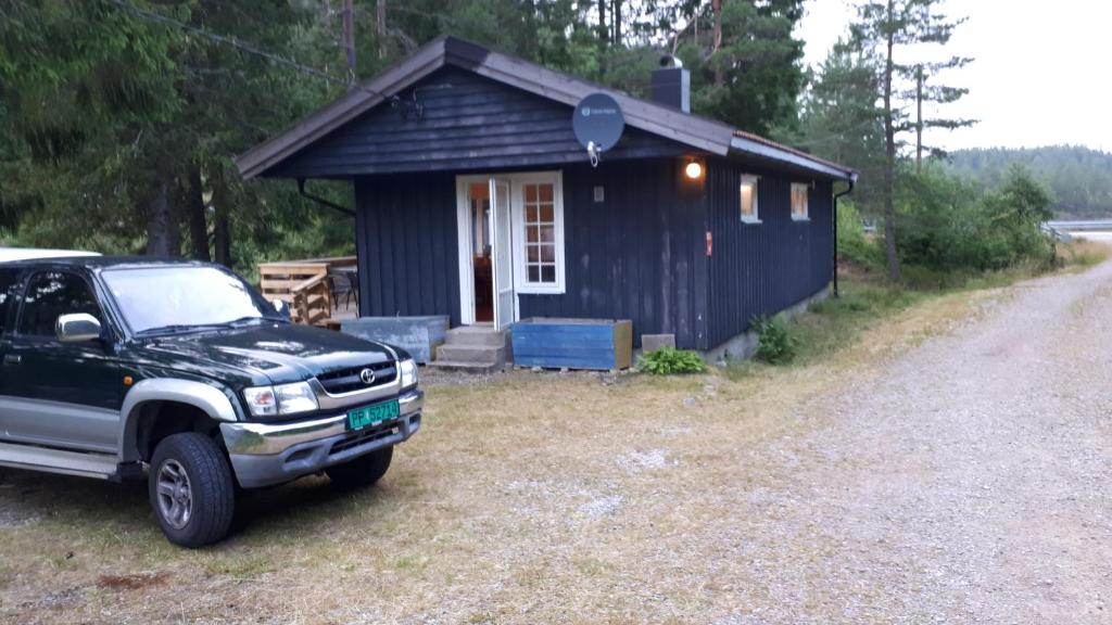 Ein schwarzer Truck parkt vor einem winzigen Haus. in der Unterkunft Granheim Hytte med 2 soverom in Birkeland