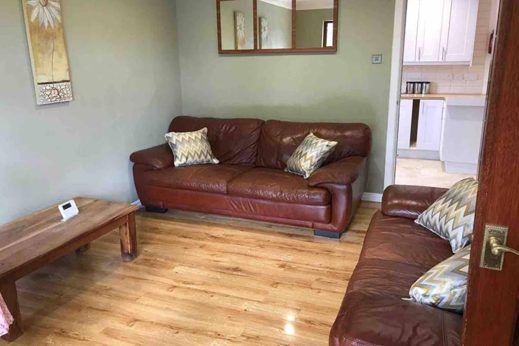 a living room with a brown leather couch and a table at Bangor Home from Home 2bed house in Bangor