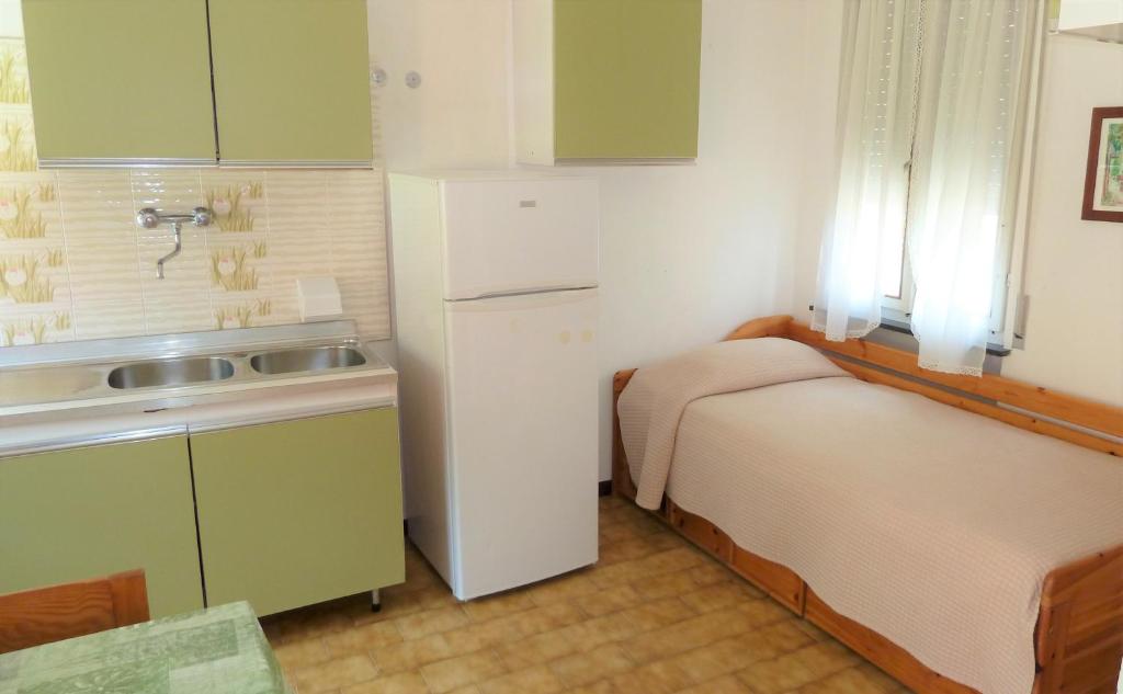 a small kitchen with two beds and a refrigerator at Camping Alpino - Nature Village in Malcesine