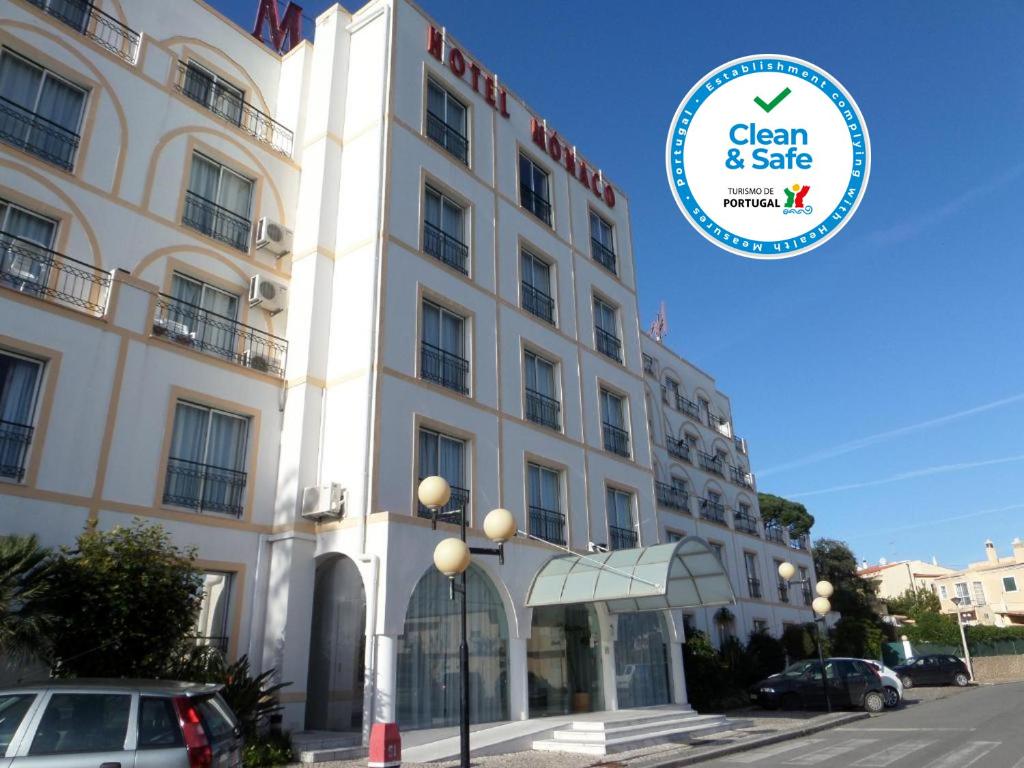 een groot wit gebouw met een bord ervoor bij Hotel Monaco in Faro