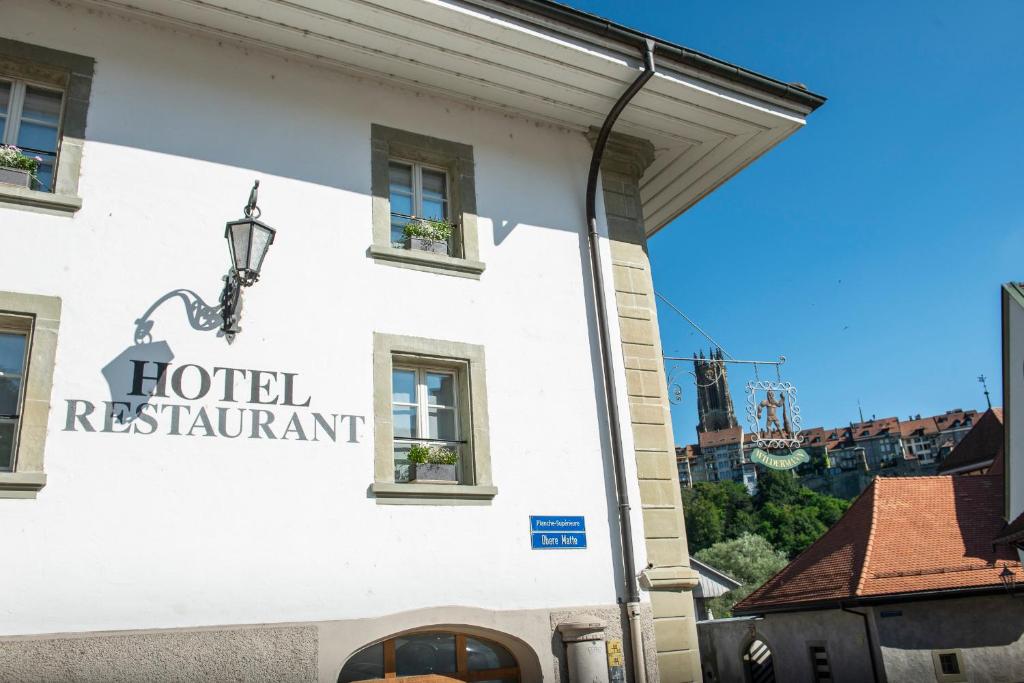 ein Schild für ein Hotelrestaurant an der Seite eines Gebäudes in der Unterkunft Le Sauvage in Freiburg im Üechtland