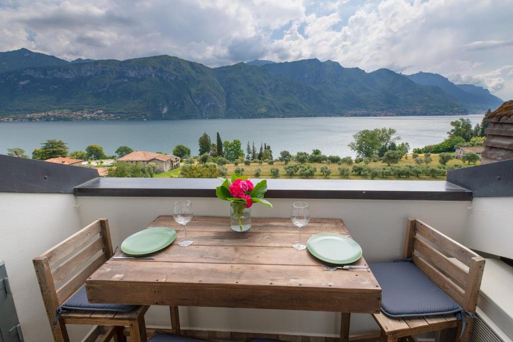una mesa de madera con un jarrón de flores en el balcón en Max Apartment, en Bellagio