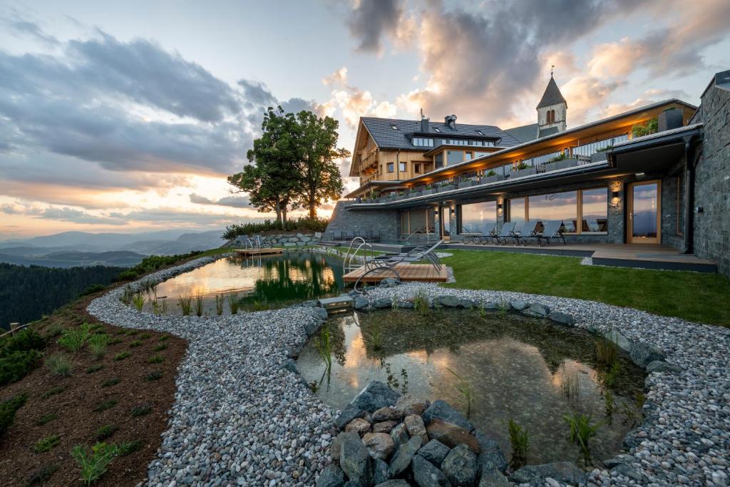 ザンクト・ファイト・アン・デア・グランにあるGipfelhaus Magdalensbergの池のある丘の上の家