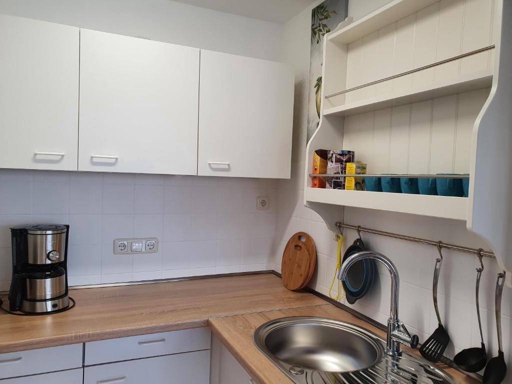 a kitchen with white cabinets and a sink at LA CASITA in Düren - Eifel