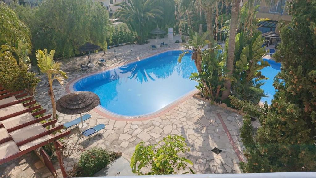 uma vista sobre uma piscina com cadeiras e árvores em Sea view Apartment Peyia, Paphos em Pafos