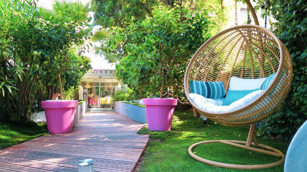 une chaise en osier assise sur une promenade dans un jardin dans l'établissement Cézanne Hôtel Spa, à Cannes