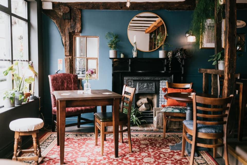 une salle à manger avec une table, des chaises et une cheminée dans l'établissement The Old Bakery, à Kenilworth