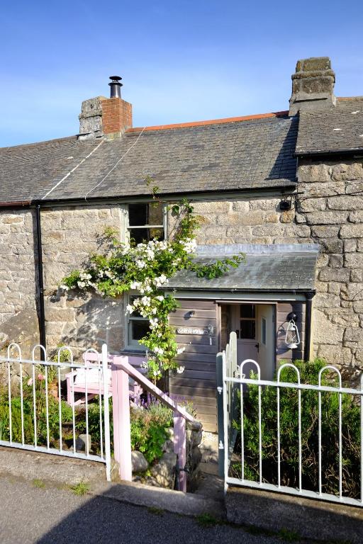 an old stone house with a gate in front of it at Niver Dew Holiday Cottage in Lower Boscaswell