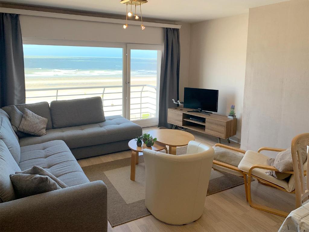 a living room with a couch and a table and a television at Beach View Five in Blankenberge