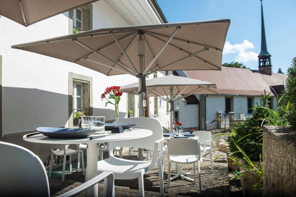 un patio con tavoli, sedie e ombrelloni di Le Sauvage a Friburgo