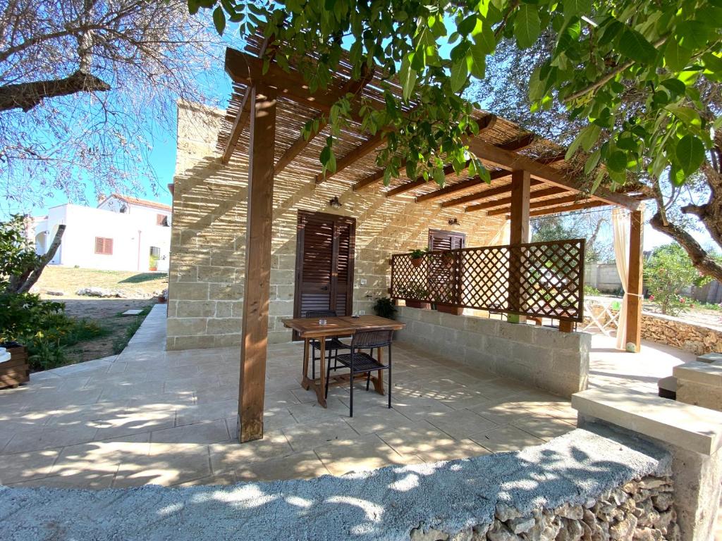 una mesa de madera y un banco bajo una pérgola de madera en Le stanze di Ray, en Borgagne