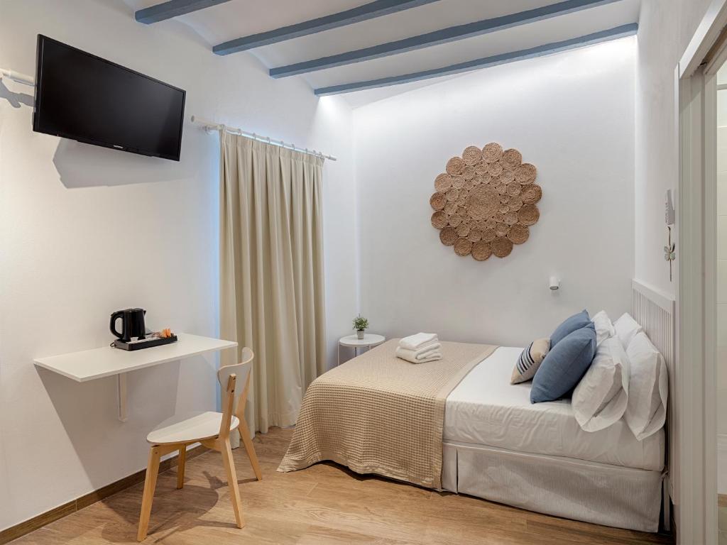 a bedroom with a bed and a desk and a television at Hostal Altea House in Altea