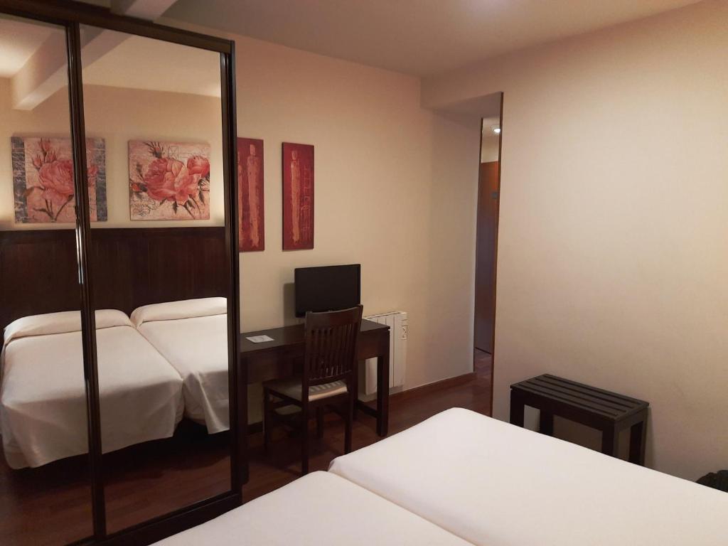 a hotel room with a bed and a desk and a mirror at Hotel Urogallo in Vielha