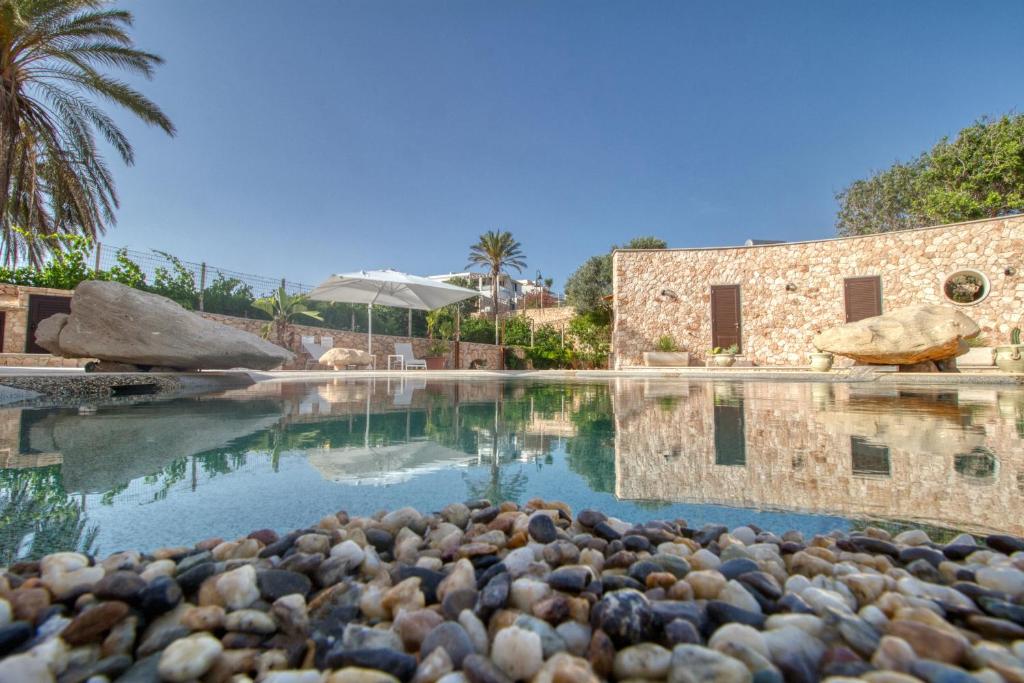 a pool of water with rocks in front of a building at Residence Il Corallo - Guitgia in Lampedusa