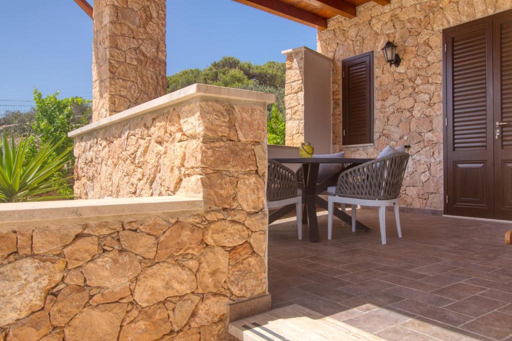 a patio with a table and chairs and a stone wall at Residence Il Corallo - Guitgia in Lampedusa