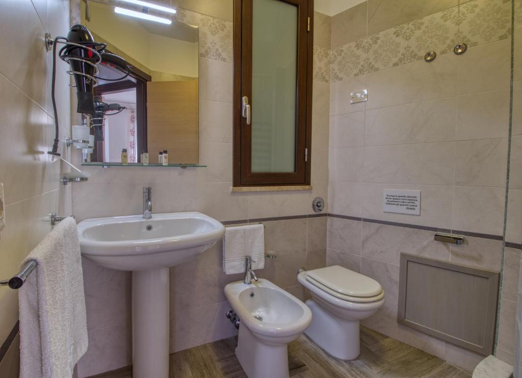 a bathroom with a sink and a toilet and a mirror at Residence Il Corallo - Guitgia in Lampedusa