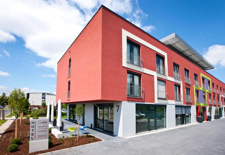 un edificio rojo y blanco con un cartel delante en Hotel Soho, en Landau in der Pfalz