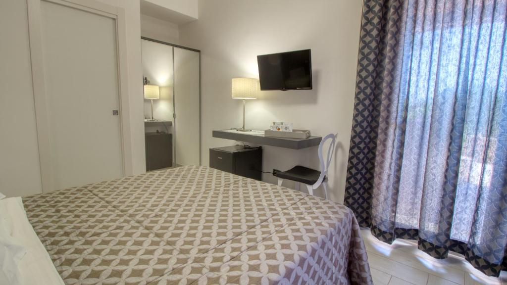 a hotel room with a bed and a desk and a window at Residence Il Corallo - Guitgia in Lampedusa