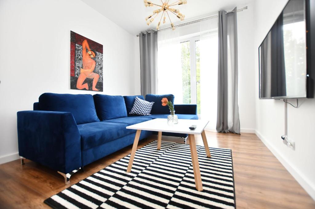 - un salon avec un canapé bleu et une table dans l'établissement Wolski Apartments - Jagiellońska 17, à Kołobrzeg