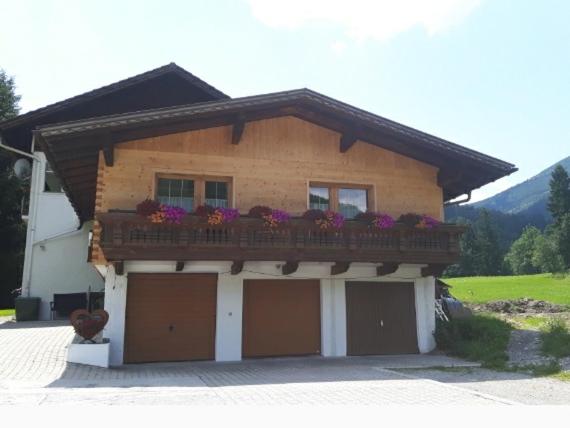 a house with a balcony with flowers on it at Gästehaus Koch in Zöblen