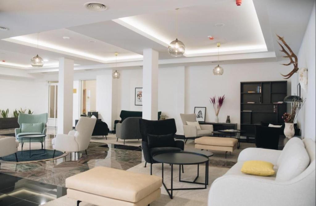 a lobby with white chairs and tables and chairs at Imperia Apartments in Vrnjačka Banja