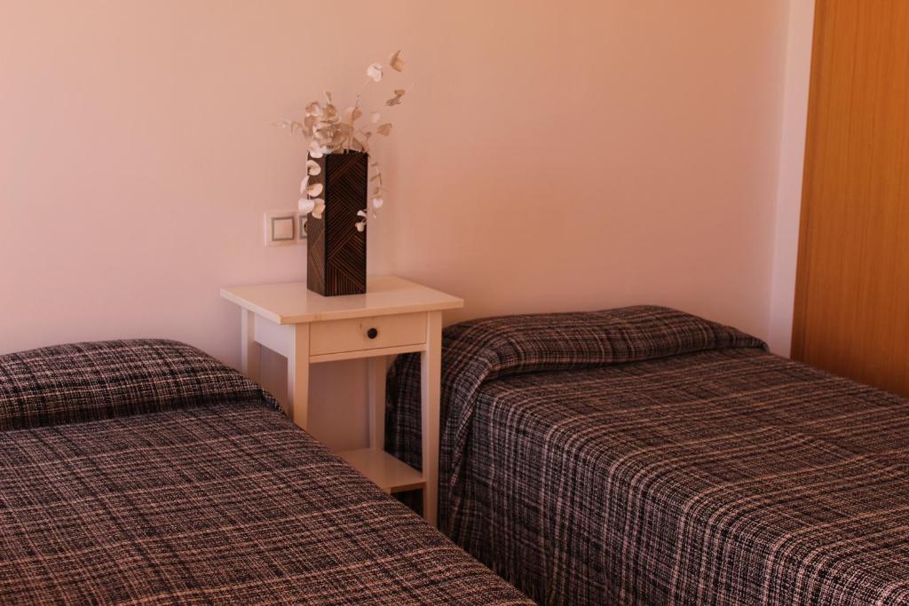 デニアにあるJardines Del Montgo VyBのベッド2台、テーブル(ボックス付)が備わる客室です。