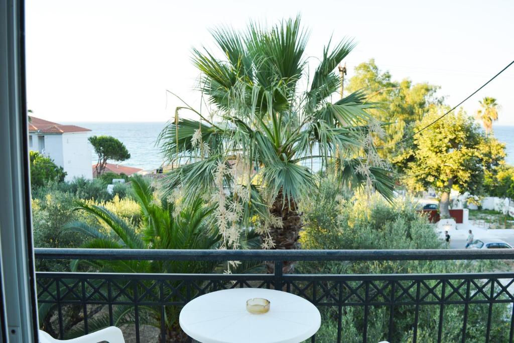 uma palmeira numa varanda com uma mesa em Paradise Beach Apartments em Argasi