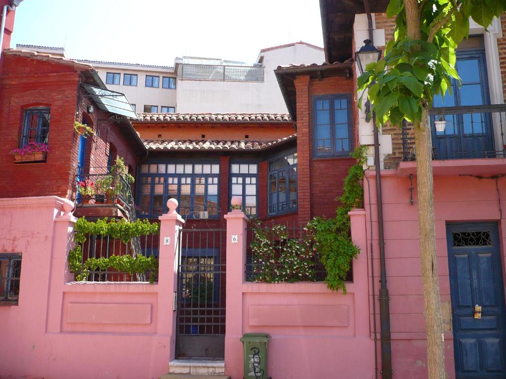 una casa rosa con una puerta y una valla en El 8 de Serranos, en León