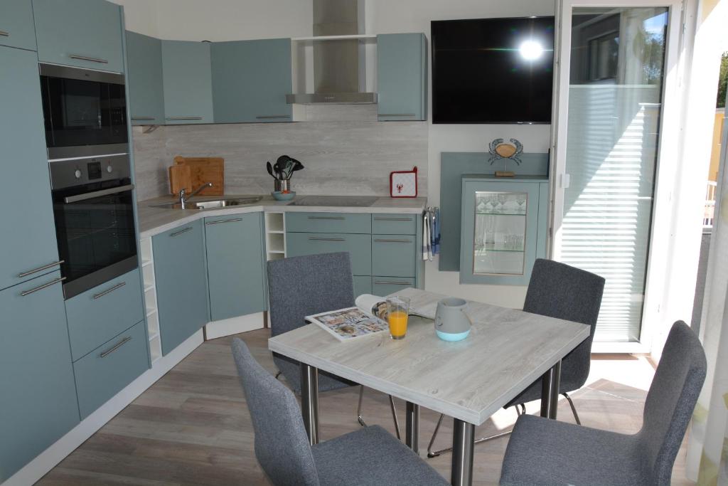 eine Küche mit blauen Schränken sowie einem Tisch und Stühlen in der Unterkunft Ostsee-Karo in Graal-Müritz