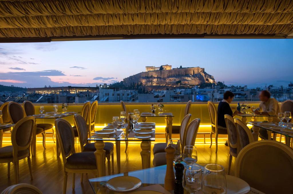 a restaurant with tables and chairs with a view ofhens at Acropolian Spirit Boutique Hotel in Athens