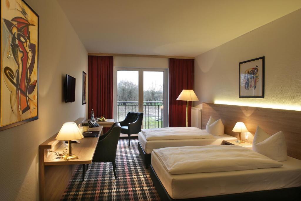 Habitación de hotel con 2 camas y escritorio en Hotel PreMotel-Premium Motel am Park, en Kassel