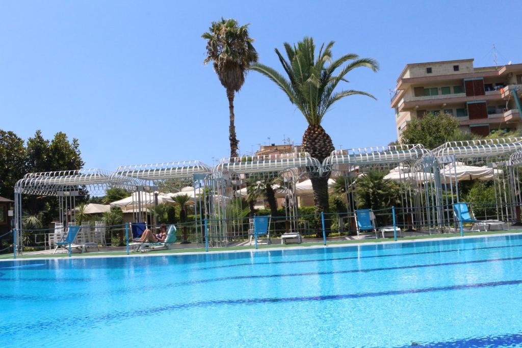 a pool with chairs and palm trees next to a building at Hotel Mirasole International in Gaeta