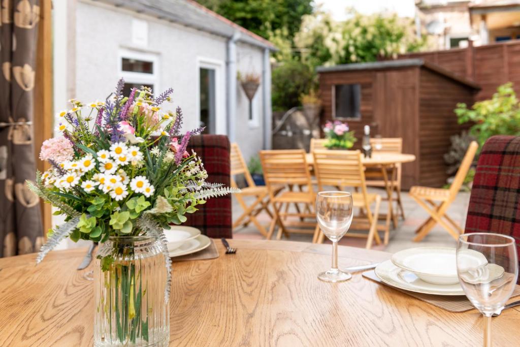 un jarrón de flores sentado en una mesa de madera en Dormie Cottage, lovely bright and spacious bungalow with wood fire en Ballater