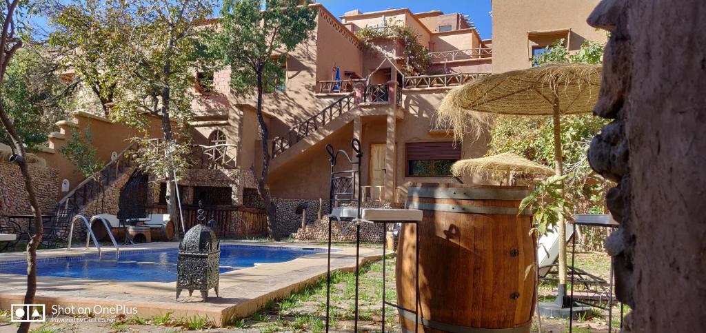 a house with a swimming pool and an umbrella at Riad Des Vieilles Charrues in Boumalne Dades