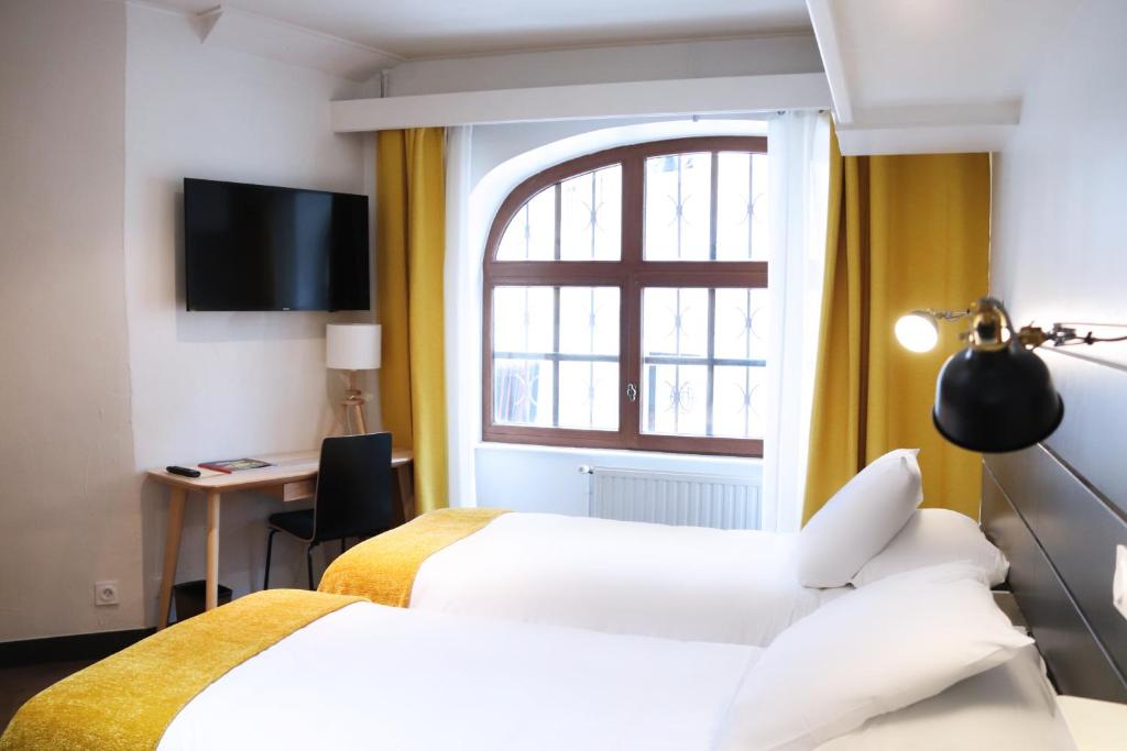 a hotel room with two beds and a window at Hotel Athanor Centre in Beaune