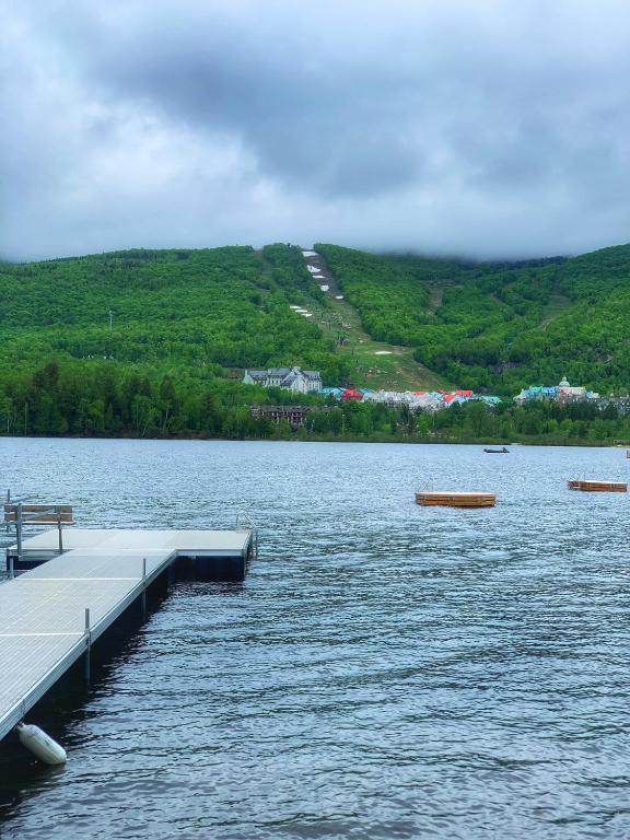 a dock on a lake with mountains in the background at Auberge Le Lupin-Self Check-in in Mont-Tremblant