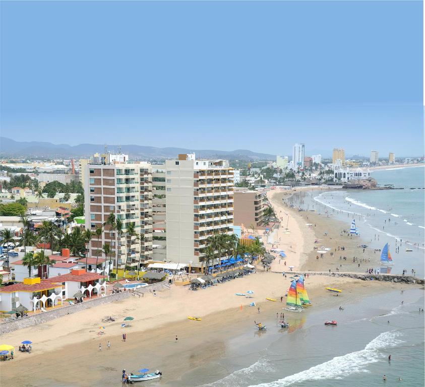 a beach with people and buildings and the ocean at Las Flores Beach Resort in Mazatlán