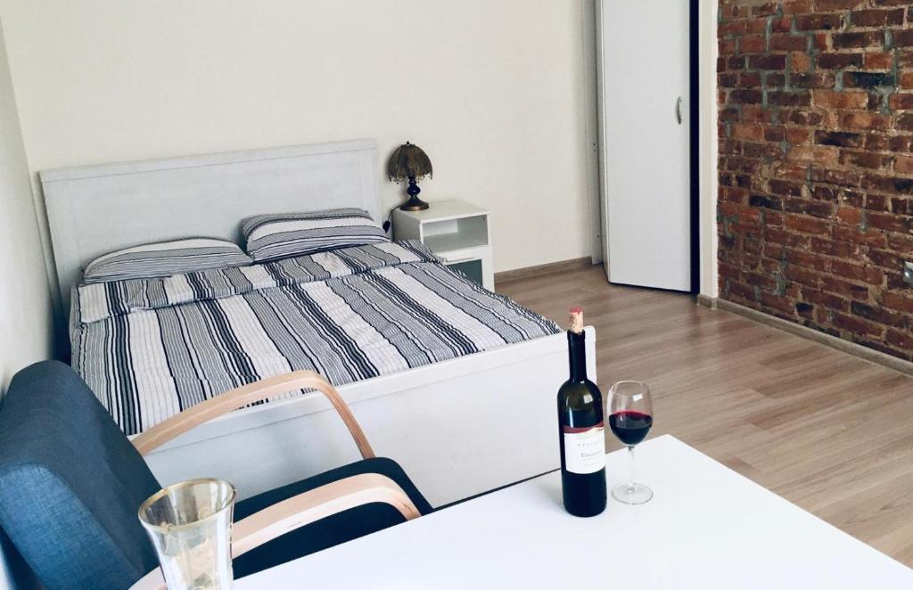 a bedroom with a bed and a bottle of wine on a table at Apartament Gdańsk Szklana Huta in Gdańsk