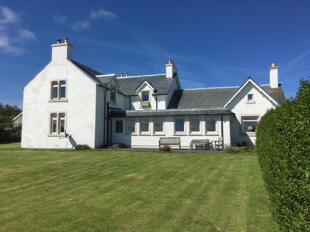 a large white house with a large yard at Caberfeidh Cottage in Bruichladdich