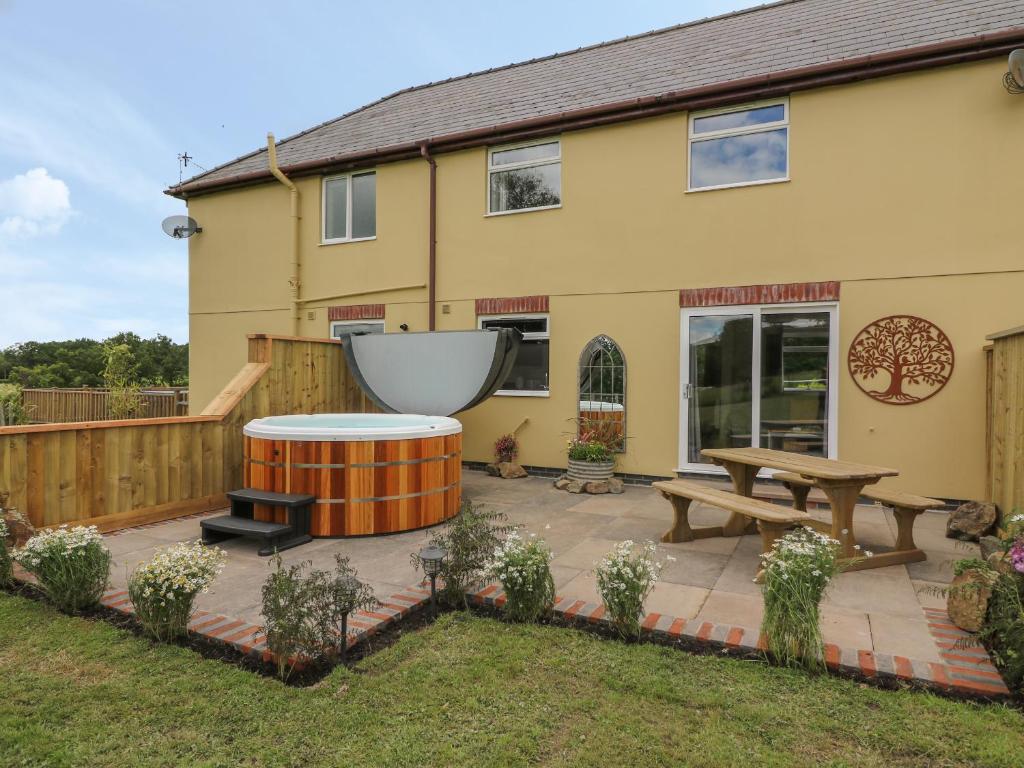 un patio con una mesa y un banco frente a una casa en Owl Cottage, en Llandrindod Wells