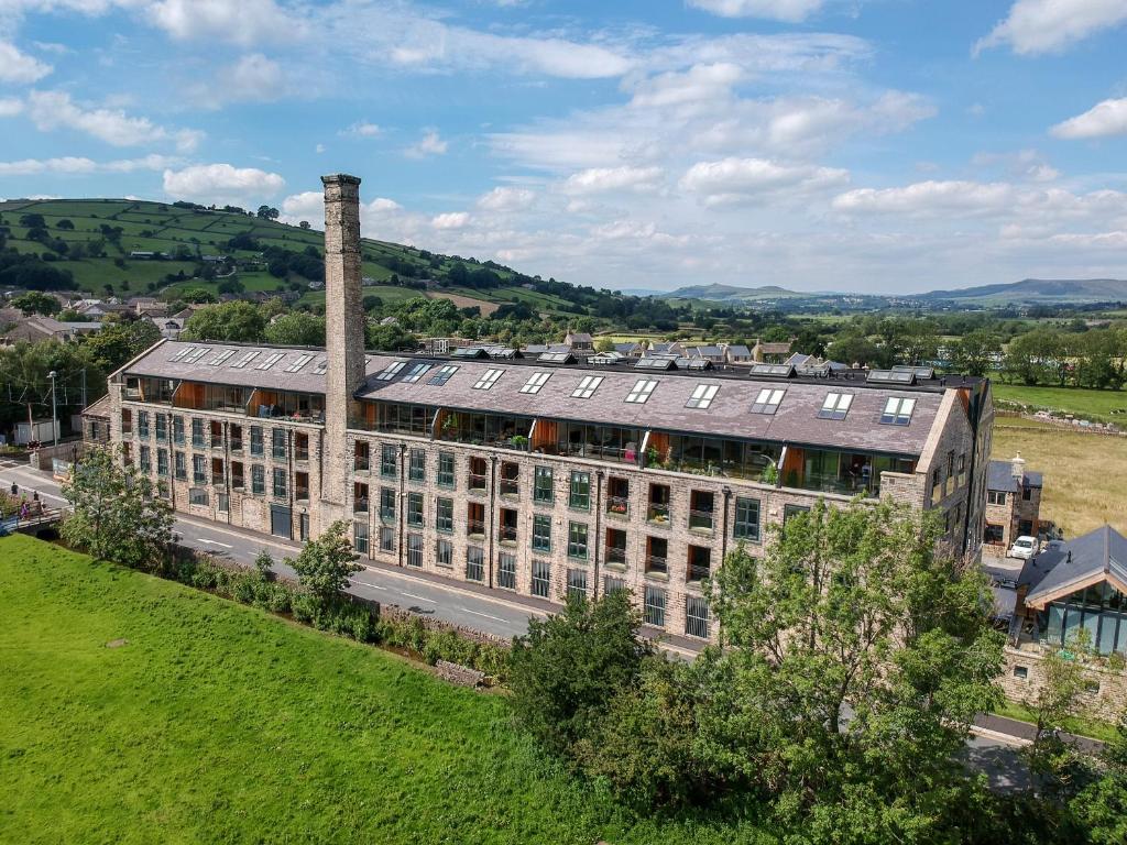 a large building with a chimney and a green field at The Works in Cononley