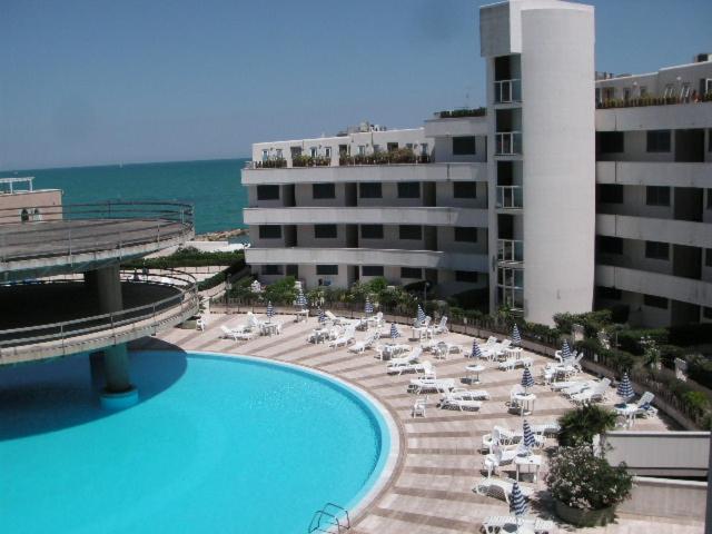 widok na hotel z basenem, krzesłami i budynkami w obiekcie Appartamento su Residence Paradiso Azzurro w mieście Porto Recanati